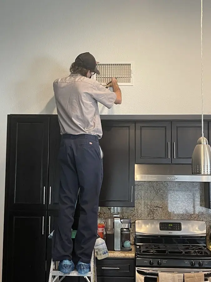 Technician inspecting an air vent during HVAC service in Adelphi